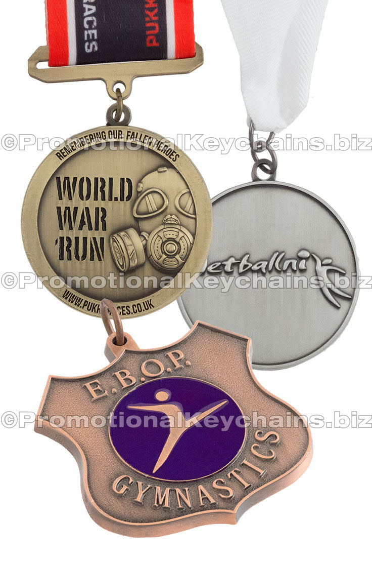 Three different medals are displayed: an antiqued brass medal for emblazoned with a gas mask and "WORLD WAR RUN", attached to a black, white and red ribbon, an antiqued nickel medal for a sports event attached to a white ribbon, and an antiqued copper medal, shaped like a shield with a purple enamel emblem in the center and the text "E.B.O.P. GYMNASTICS" around the outside.