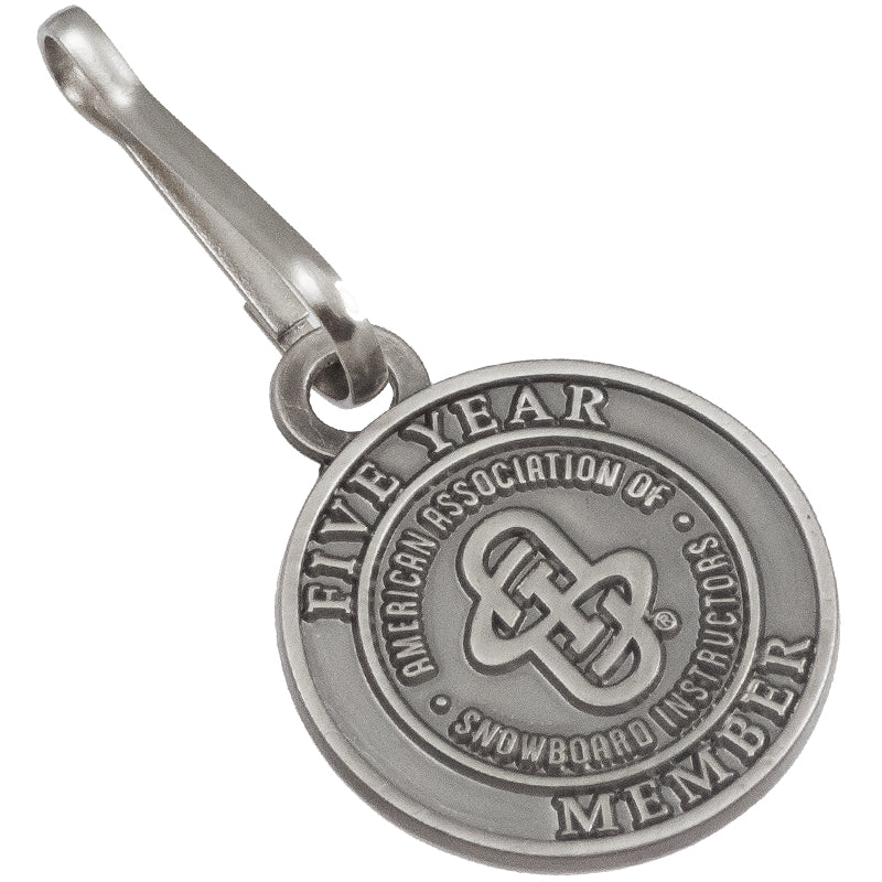 A round, antiqued nickel zipper pull displaying "American Association of Snowboard Instructors" branding.