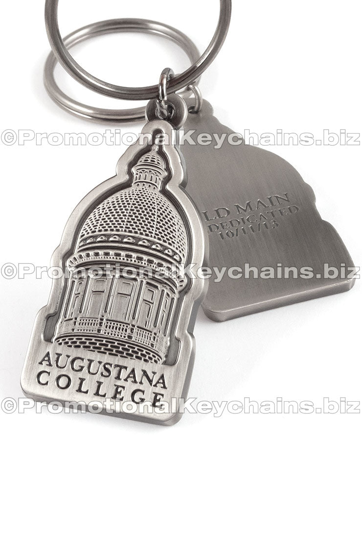 The front and back of an antiqued nickel keychain featuring a dome-shaped building with "Augustana College" debossed underneath, also featuring text debossed on the back side.