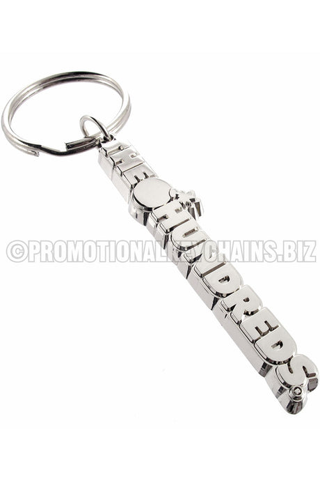 A long, polished nickel keychain shaped to the words "THE HUNDREDS," with a bomb symbol between the two words.