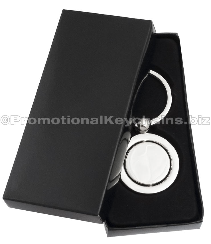 A polished keychain featuring a round spinning disc in the center, displayed in a black gift box.