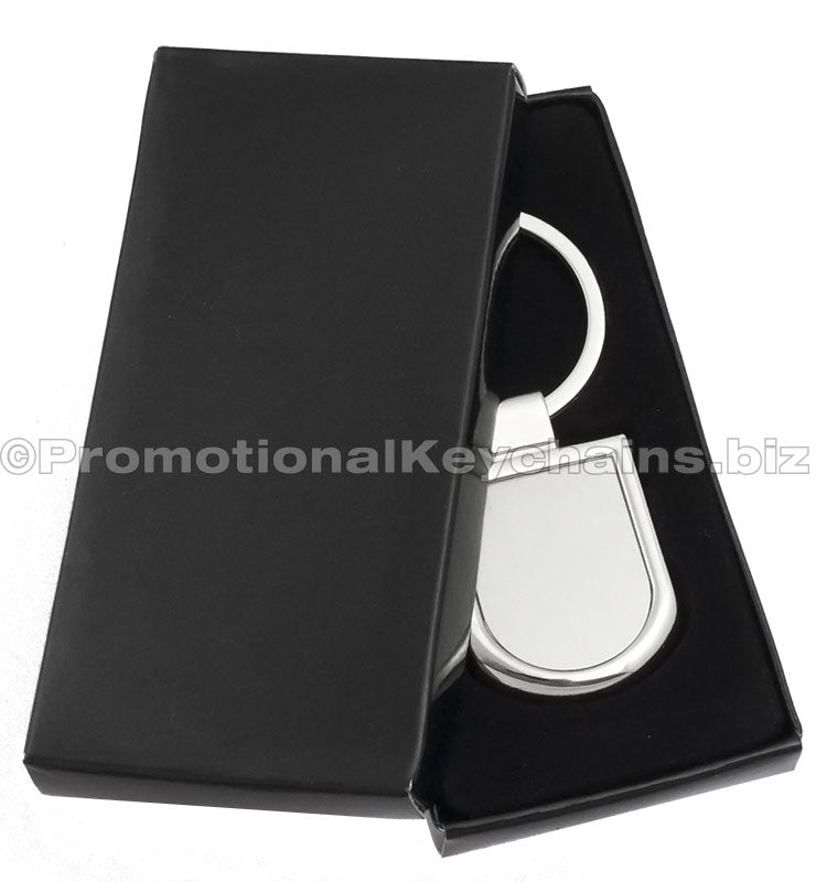 A polished silver keychain featuring a badge-shaped pendant displayed in a black gift box.