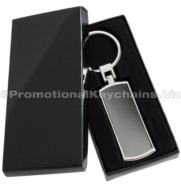 A polished metal keychain with a black inlay displayed in a black gift box.