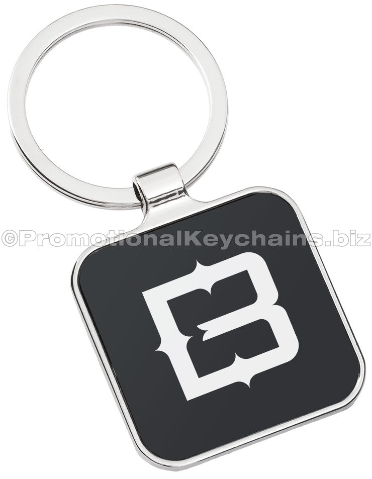 A polished metal keychain featuring a square black background with a bold letter "B" logo engraved in the center.