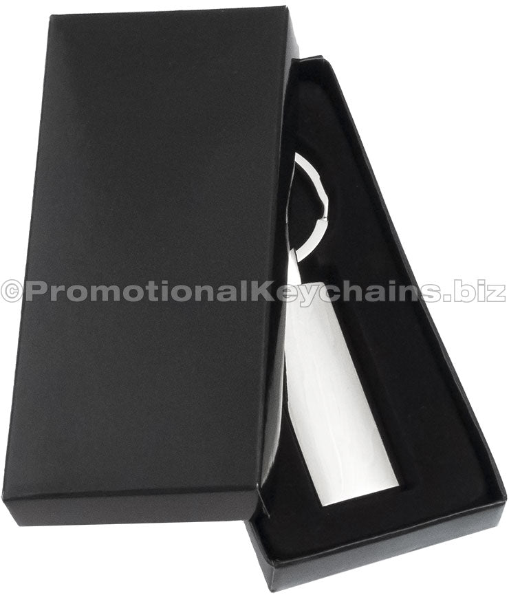 A rectangular polished metal keychain displayed in a black gift box.