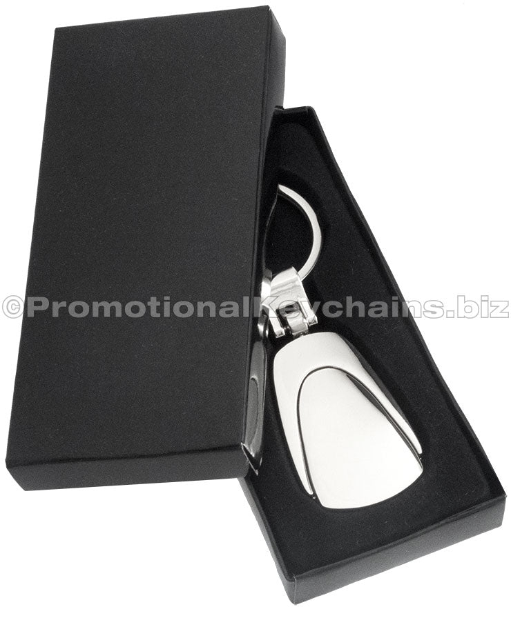 A polished metal fob keychain displayed in a black gift box.