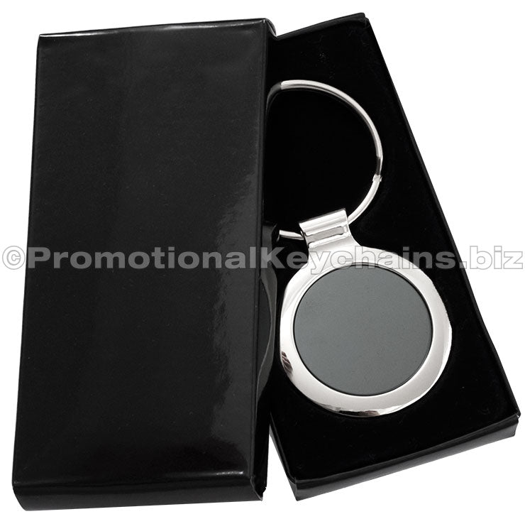 A circular polished metal keychain featuring a black inlay displayed in a black gift box.