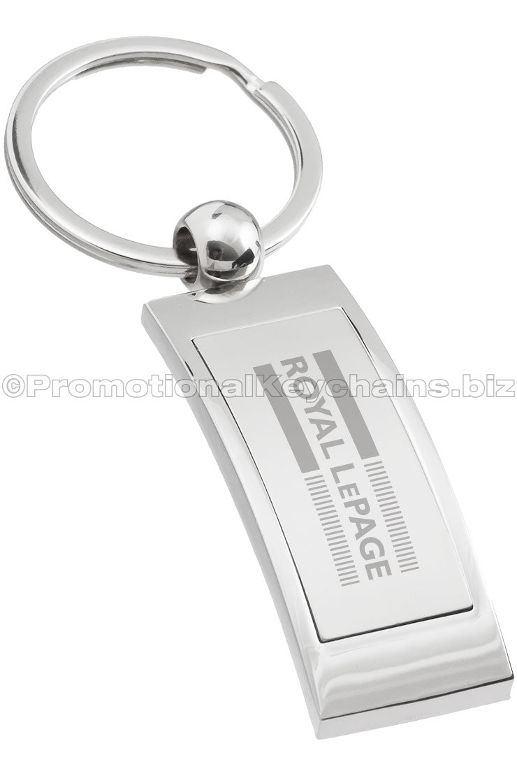 A curved, polished metal keychain that is rectangular in shape, featuring the "Royal LePage" logo engraved on the center.