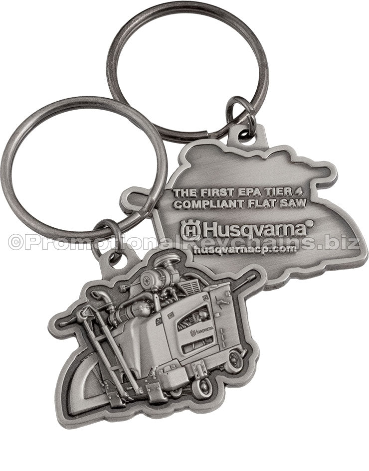 Both sides of an antiqued nickel keychain featuring a detailed, 3-dimensional flat saw design and text embossed on the back side.