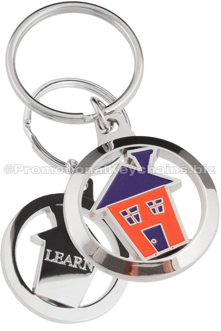 The front and back of a circular polished nickel keychain, the front featuring a house design in red and blue hard enamel and the back featuring the text "LEARN" debossed into the metal.