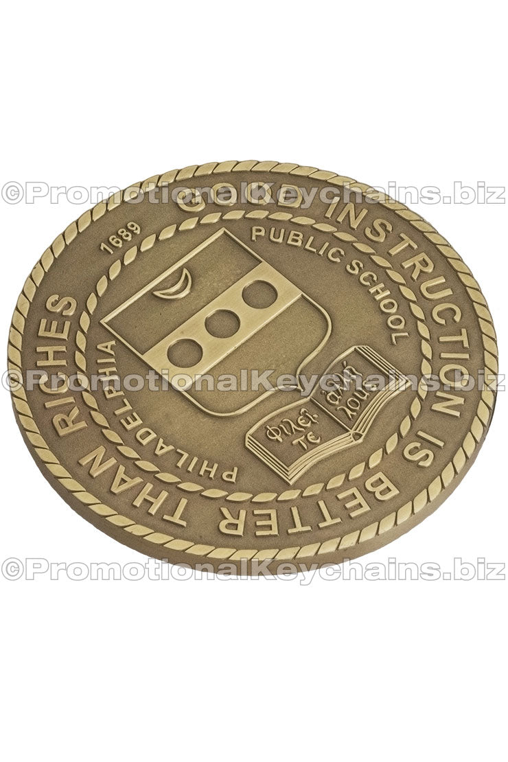 An antiqued brass coaster featuring a Philadelphia Public School logo, surrounded by a rope border.