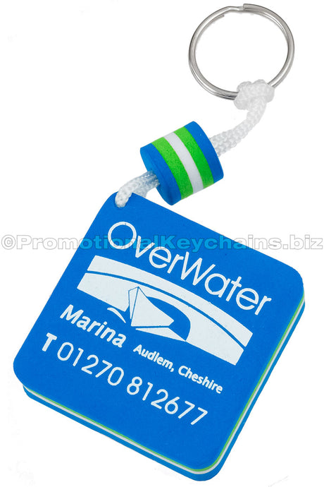 A blue, white, and lime green floating foam keychain, square in shape, with "OverWater Marina" and contact information printed in white.