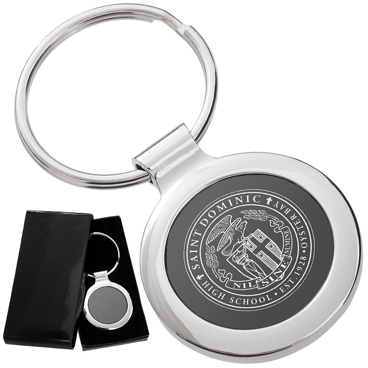 There are two images. On the left, a circular polished metal keychain featuring a black inlay displayed in a black gift box. On the right is the same keychain with a logo clearly engraved in the center.