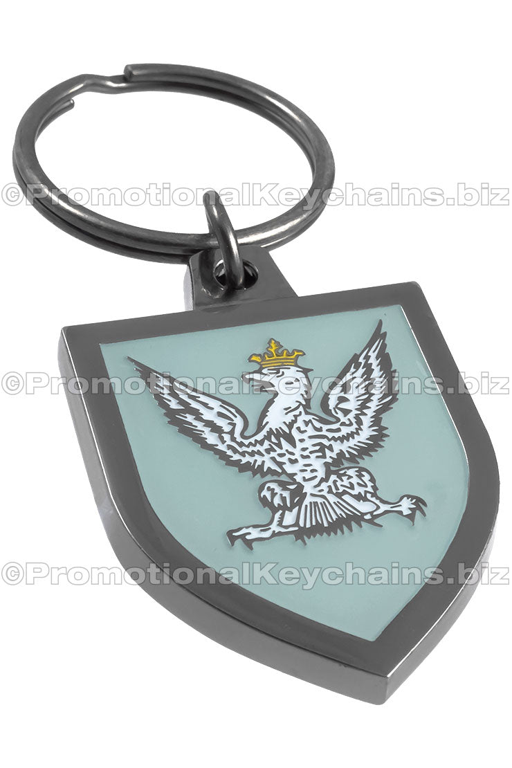 A shield-shaped, polished black nickel keychain featuring a coat of arms with a crowned eagle design and a mint green enamel color background.