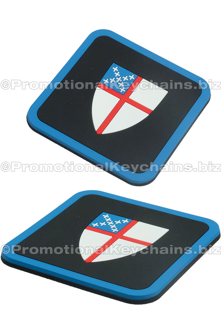 Two angles of the same square PVC coasters featuring a white shield with a red cross and blue accents set against a black background.