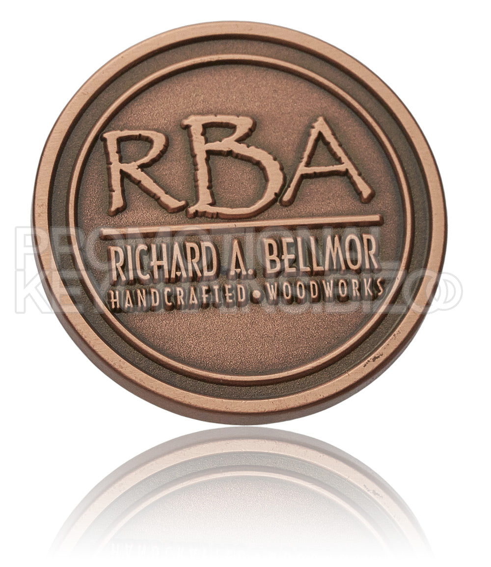 A circular, antiqued copper medallion, featuring the branding of "Richard A. Bellmor Handcrafted Woodworks" embossed prominently on its surface.