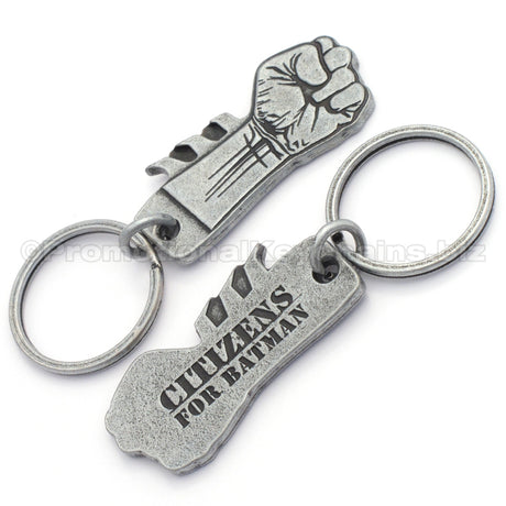 The front and back an antiqued nickel keychain featuring a clenched fist design on the front with "Citizens for Batman" debossed on the backside.