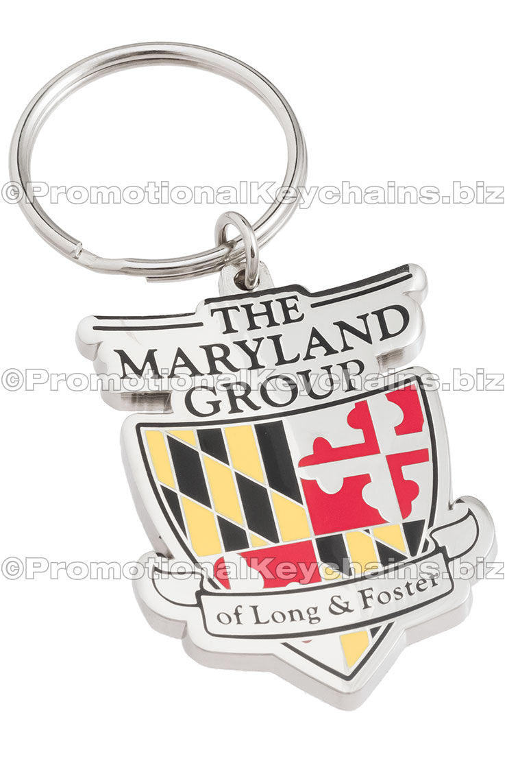 A polished nickel keychain featuring "The Maryland Group" logo with a shield design in Maryland's colors of black, yellow, and red.