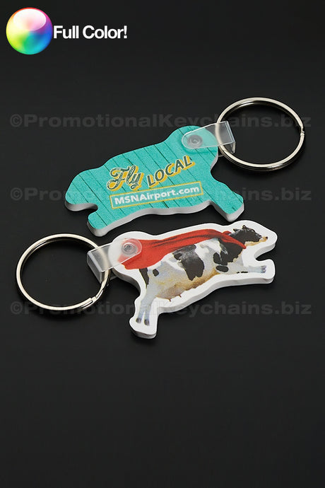 Custom Shaped Vinyl Keychains in Full Color of a cow wearing a red cape and FLY LOCAL on the reverse side in yellow and blue.