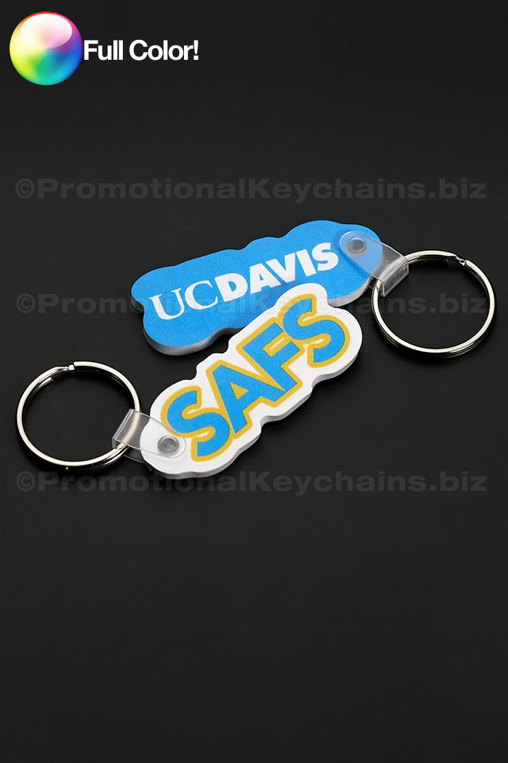 Blue and white vinyl keychains on a dark background with the UCDAVIS and SAFS logos.