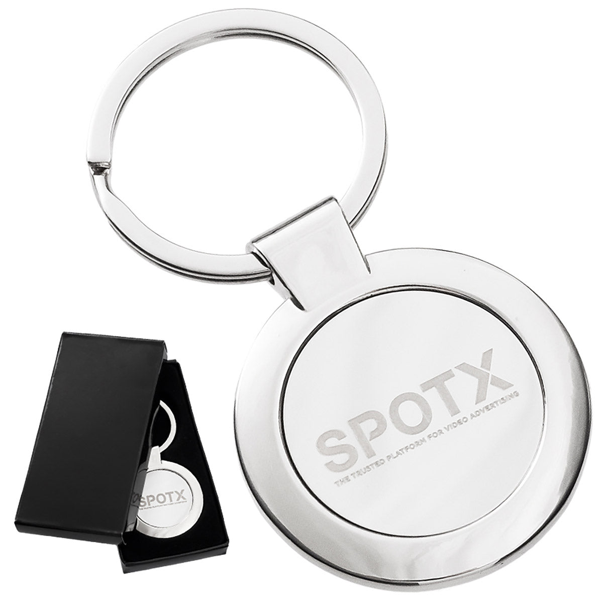 There are two images. On the left, a polished circular metal keychain featuring an engraving and displayed in a black gift box. On the right is the same keychain with a logo clearly engraved in the center.