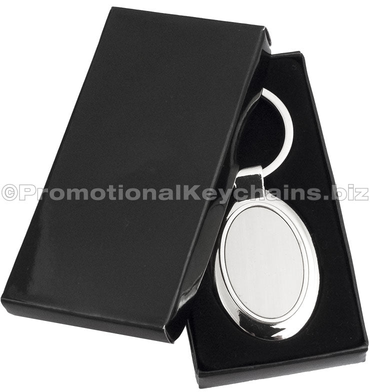An ovular polished metal keychain displayed in a black gift box.