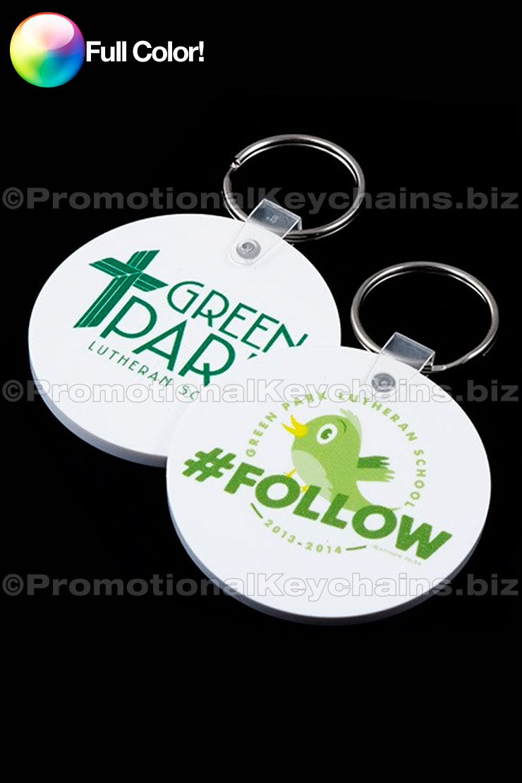 Two round vinyl keychains with full color imprint. One keychain has a green imprint with 'Green Park Lutheran Church' and the other has a white imprint with 'Follow' featuring a green bird graphic.