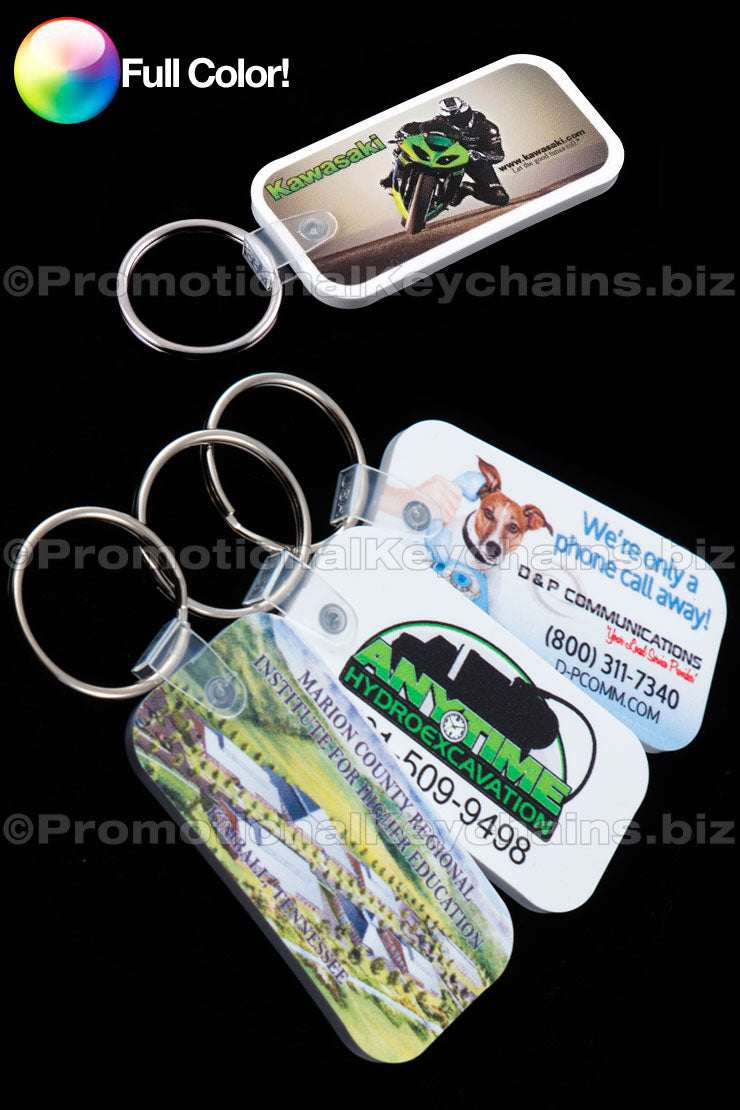 A set of full color vinyl keychains with rounded corners, featuring a promotional design for businesses. The keychains are white with a colorful imprint of a motorcycle and a dog, along with contact information for the businesses.