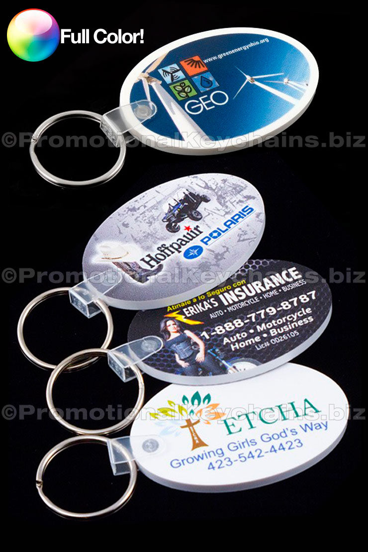 A set of full-color oval vinyl promotional keychains in various designs, including a business card design with company name and contact information, and a design featuring a satellite map with text.
