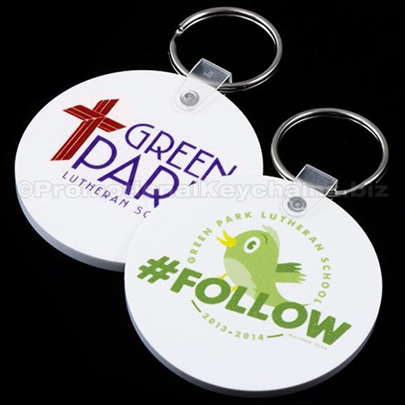 Two round vinyl keychains with full color imprint. One keychain has a purple and red imprint with 'Green Park Lutheran Church' and the other has a white imprint with 'Follow' featuring a green bird graphic.