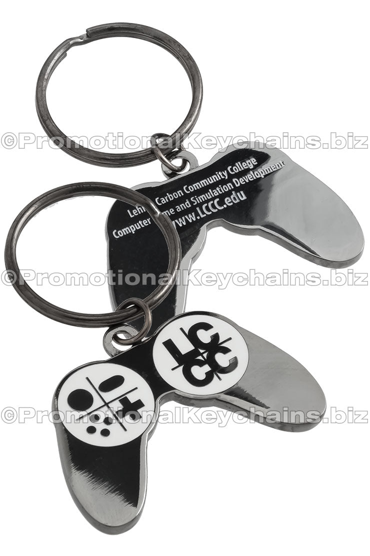 Both sides of a polished black nickel game controller-shaped keychain featuring the LCCC logo, promoting the Computer Game and Simulation Development program on the back side with debossed text.