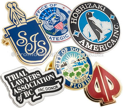 Layered image of hard enamel lapel pins showing different colors and shapes. Designs include a silver plated circle with penguin in center, another with USA eagle emblem, another design is shaped like a card spade with gold plating and red enamel.