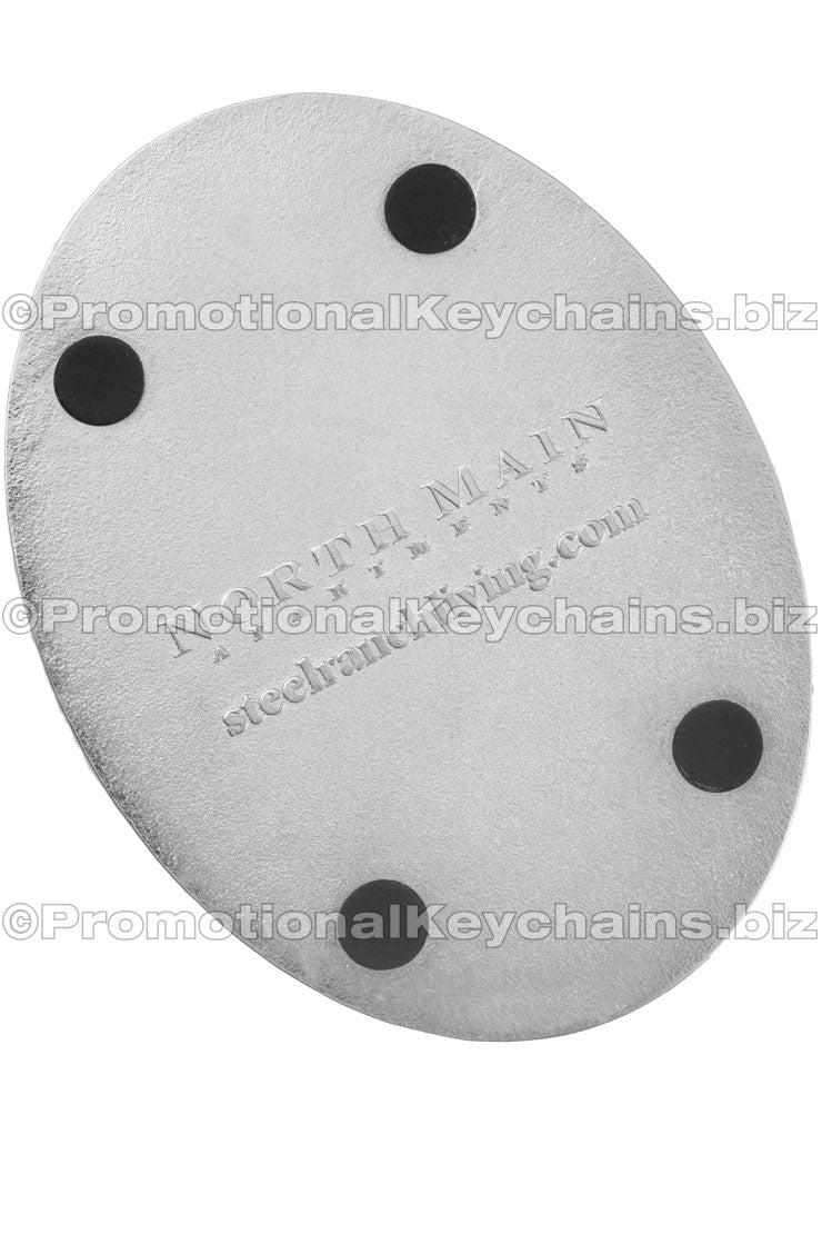 The back of a die-cast metal coaster, debossed with the North Main Apartments logo with four black coaster bumpers.