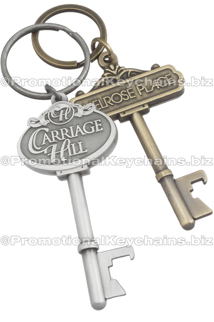 One antiqued silver and one antiqued gold key shaped bottle opener. Custom decorative designs at top of keys and key rings attached.