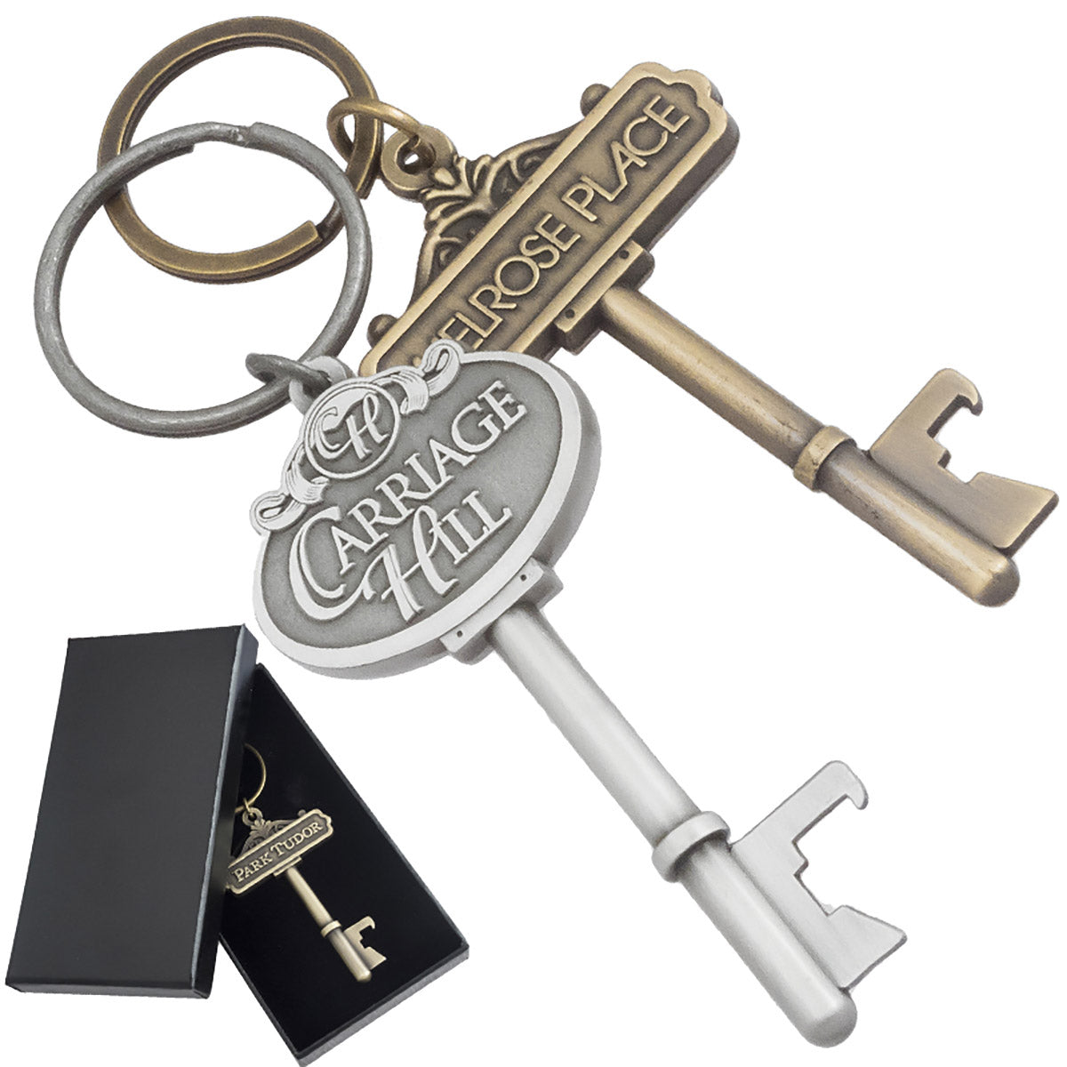 Two key shaped bottle opener keychains. Image shows keys in antiqued silver and antiqued gold. Example of custom black box in background.