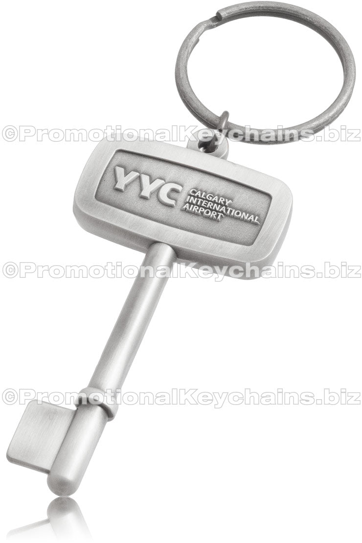 An antiqued nickel keychain shaped like a key, embossed with "YYC Calgary International Airport" in the center of the rectangular bow.