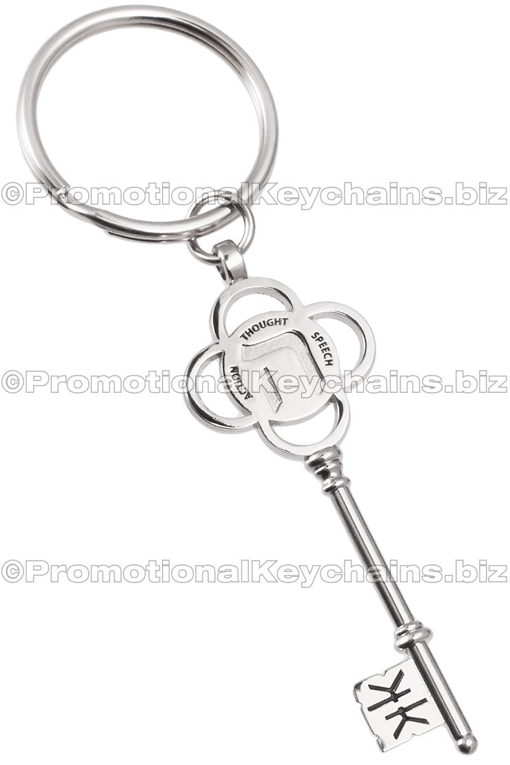 A polished nickel keychain designed as a decorative key with a four-petal flower, engraved with the words "Thought," "Speech," and "Action." The tip of the key also has a debossed design.
