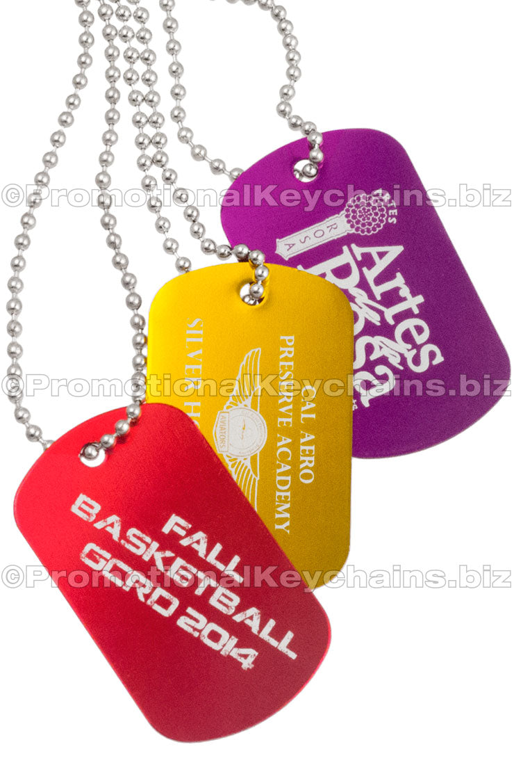 Red, gold and purple aluminum dog tags hanging from ball chains. Showing custom engraving on each tag.