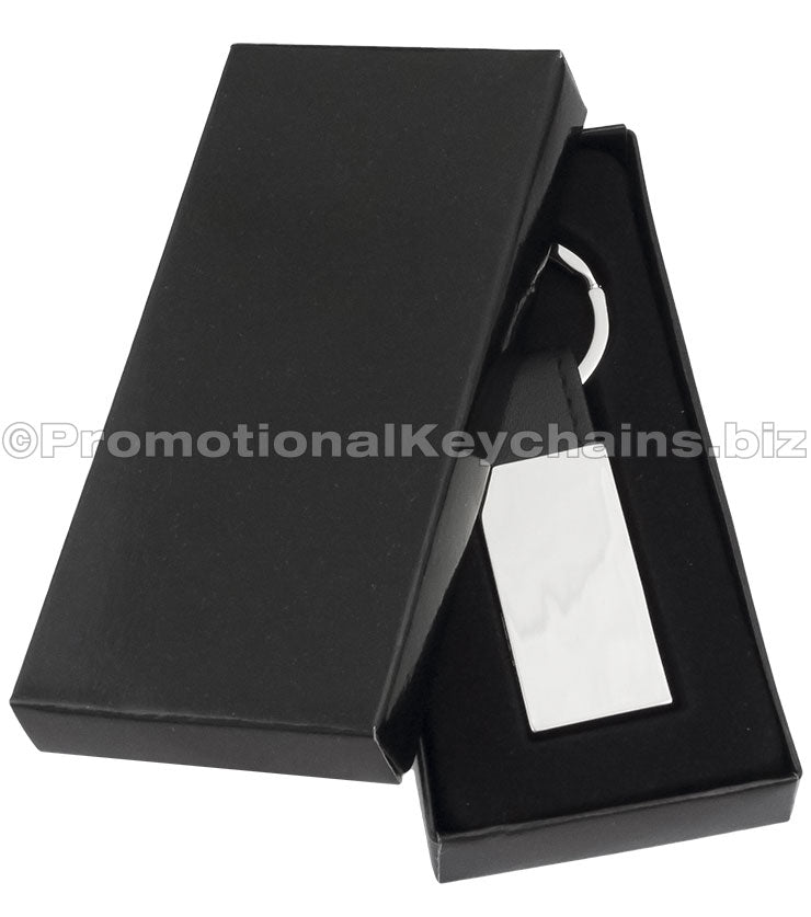A polished rectangular keychain with a black leather strap displayed in a black gift box.