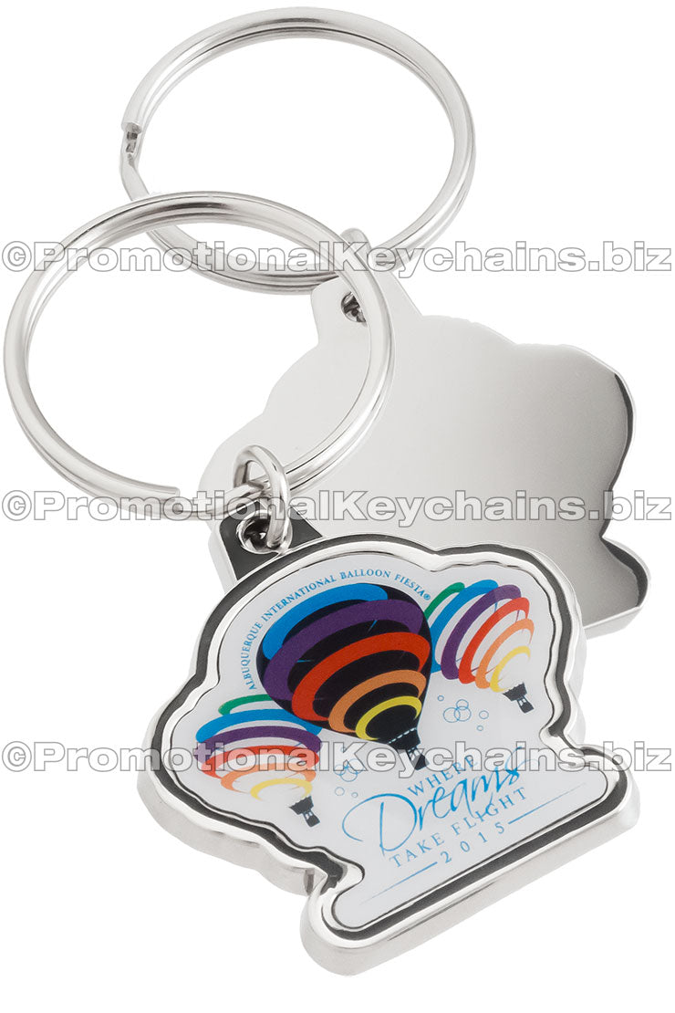 Both sides of a polished nickel keychain with a full-color imprint featuring rainbow hot air balloons and the text "Where Dreams Take Flight". The back is smooth and shiny.