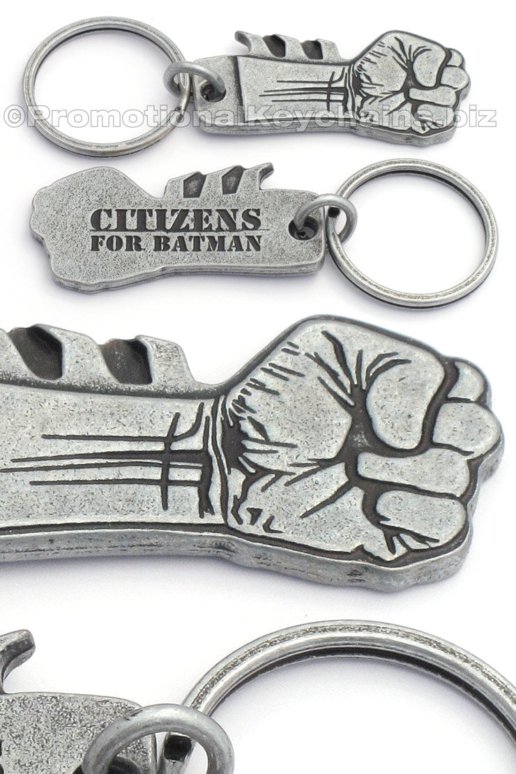 Multiple photos of an antiqued nickel keychain featuring a clenched fist design on the front with "Citizens for Batman" debossed on the backside.