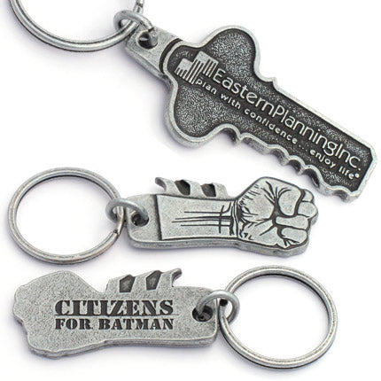 Two different antiqued nickel keychains are shown. First, a design featuring a clenched fist on the front with "Citizens for Batman" debossed on the backside. The second keychain is in the shape of a key with the logo for Eastern Planning Inc. embossed on the front.
