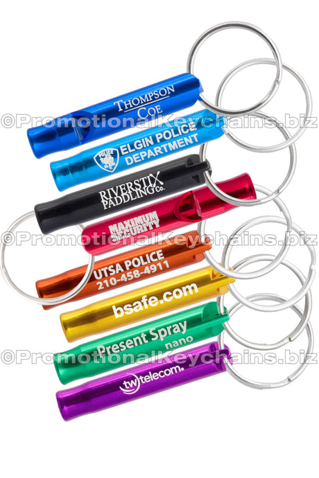 Example of the Mini Bobby Style Engraved Safety Whistles showing all the colors. Colors of whistles royal blue, aqua, black, red, orange, gold, green and purple. Each has a silvery white engraving showing custom branding.