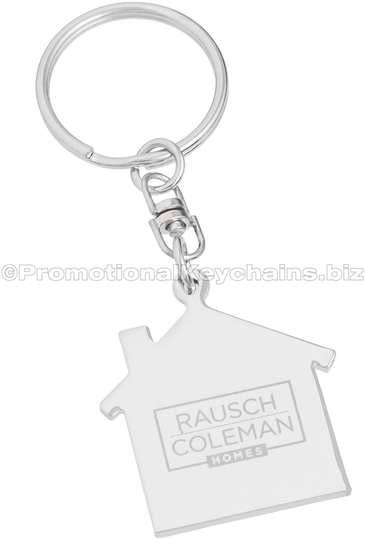The back side of a polished metal keychain in the shape of a house, engraved with the logo for Rausch Coleman Homes.