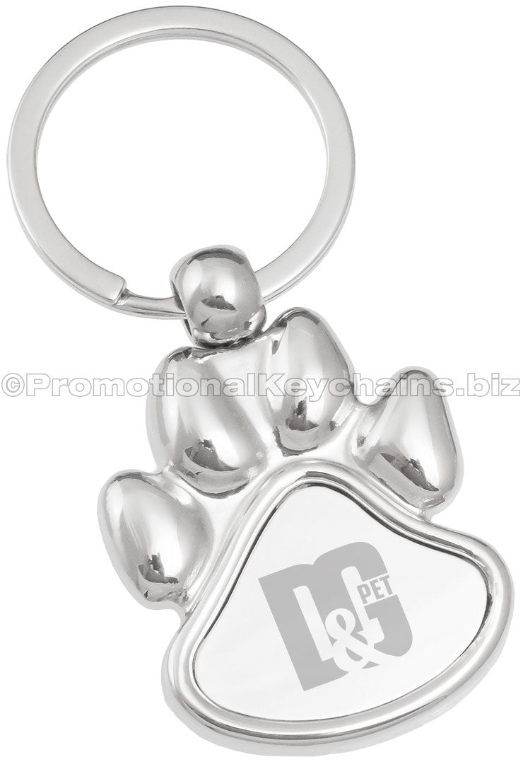 A polished metal paw-shaped keychain featuring an engraved logo in the center.