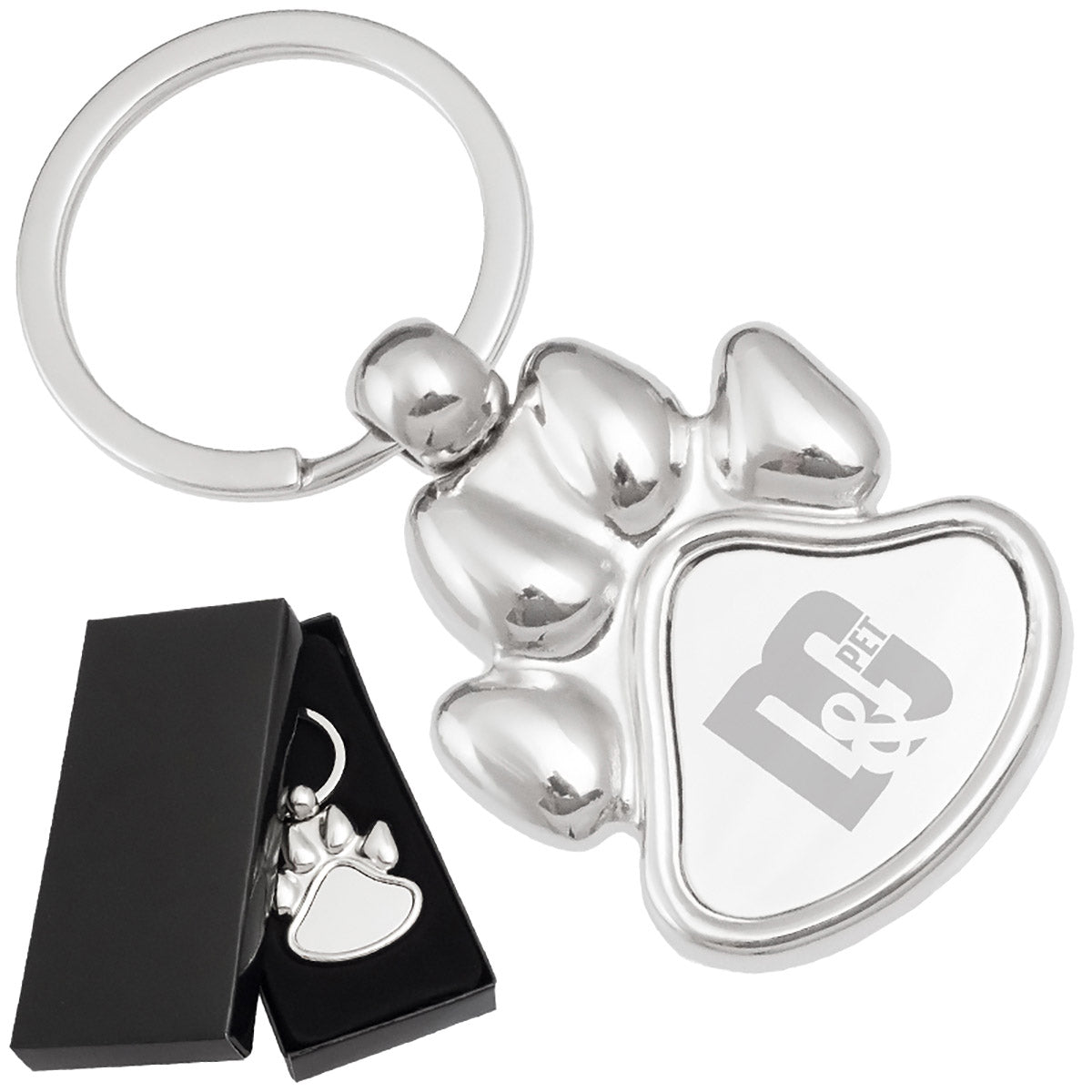 There are two images. On the left, a polished metal paw-shaped keychain displayed in a black gift box. On the right is the same keychain with a logo clearly engraved in the center.