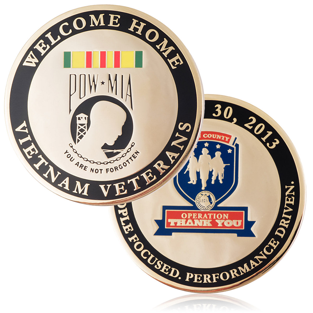 A commemorative coin for Vietnam Veterans, plated in polished brass with a black enamel color ring around the outer border, featuring "Welcome Home," the POW*MIA insignia, and various other verbiage honoring their service.