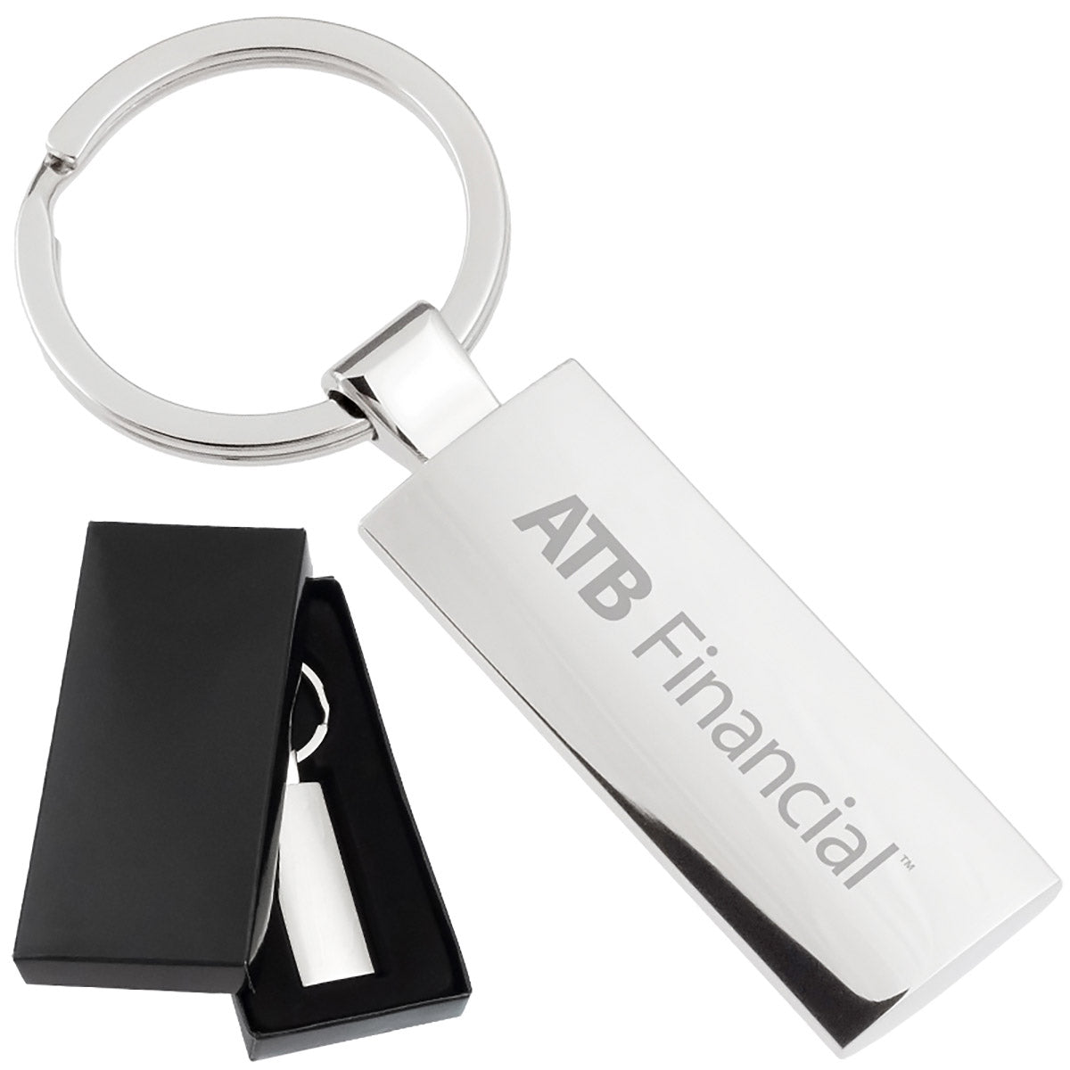 There are two images. On the left, a rectangular polished metal keychain displayed in a black gift box. On the right is the same keychain with a logo clearly engraved in the center.