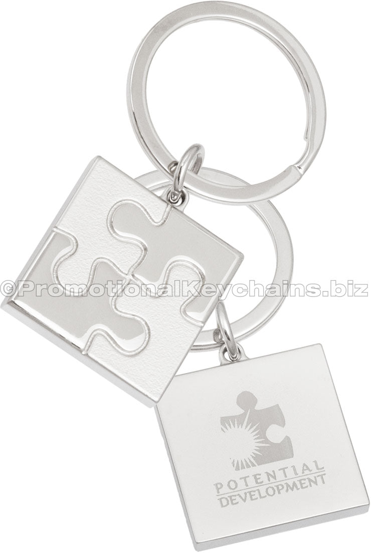 The back and front of a square keychain with a puzzle piece motif molded into the front. The back has an engraving of the logo for Potential Development.
