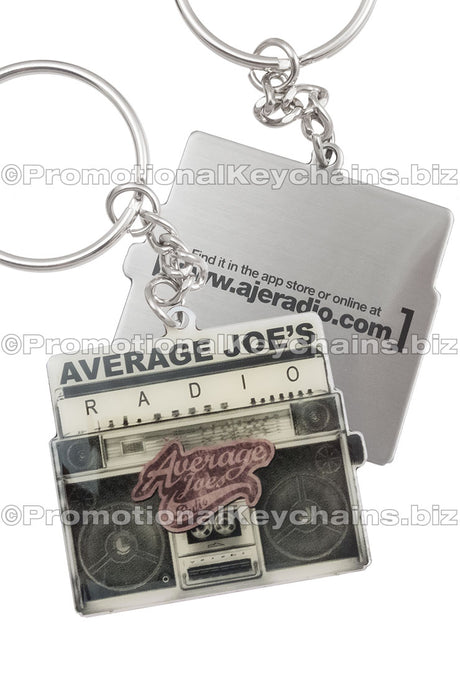Both sides of a stainless steel keychain shaped like a vintage radio with the "Average Joe's Radio" logo on the front and a website printed on the back.